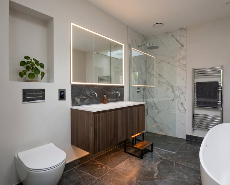 Modern bathroom with dark marble flooring, illuminated mirror cabinet above wooden vanity, wall-mounted toilet, and marble tile shower enclosure