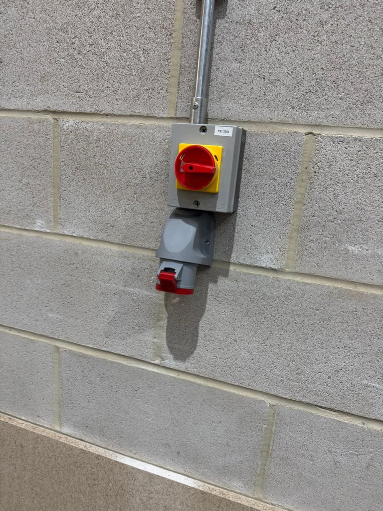 Industrial red and yellow rotary disconnect switch mounted on a concrete brick wall